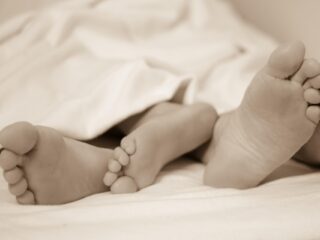 Sex first: man and woman's feet sticking out of a bed