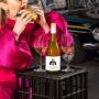 Greasy Food: Woman taking a bite of a burger with a bottle of white wine in front of her